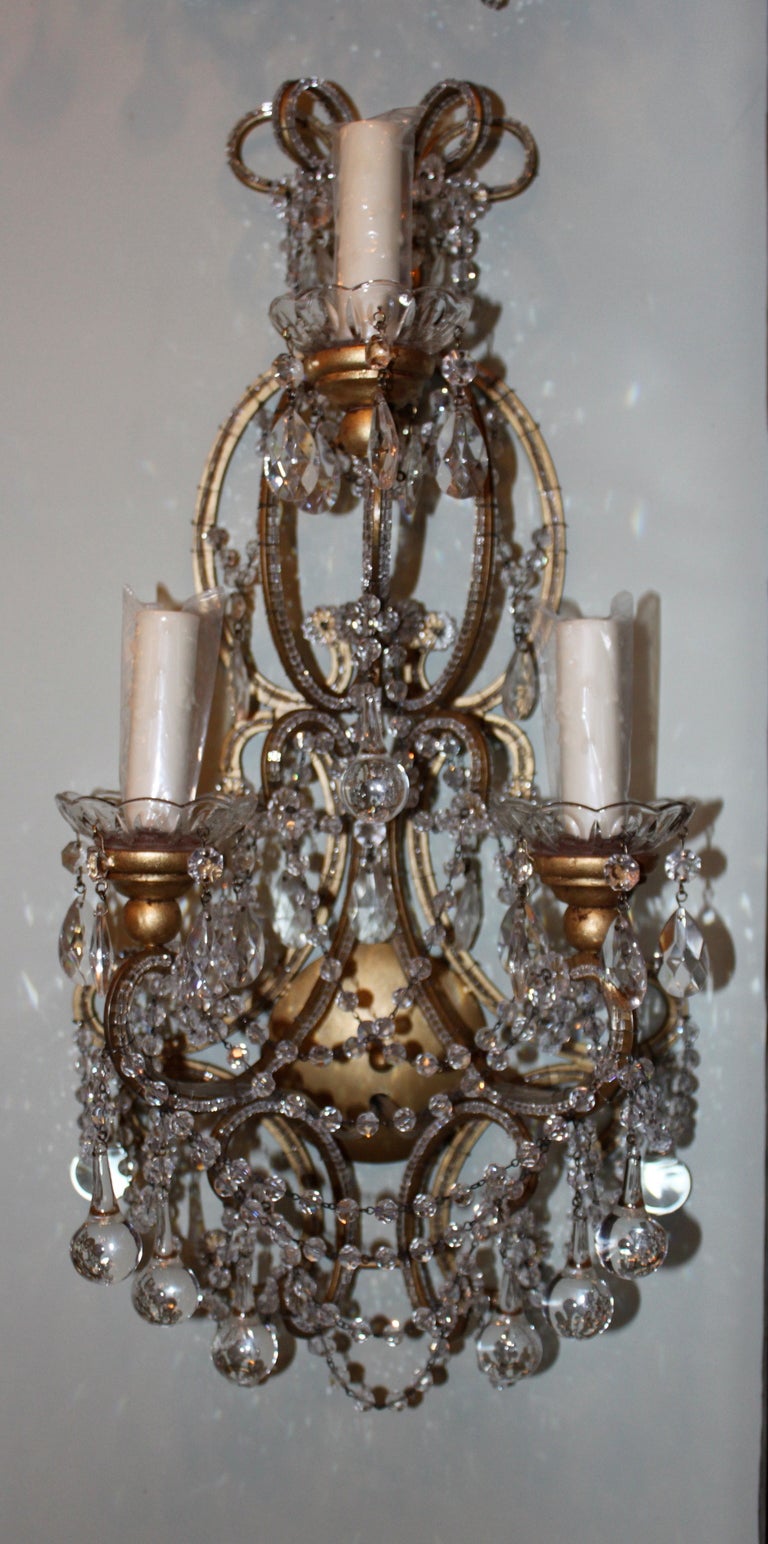 Pair of Italian style gilt metal 3-light sconces with beaded arms and English cut crystal garlands and clear crystal drops throughout.  Newly wired and in working condition.