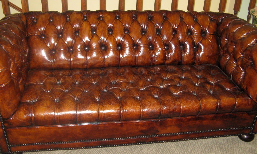Stunning leather tufted chesterfield sofa with nailhead trim detail and bun feet.