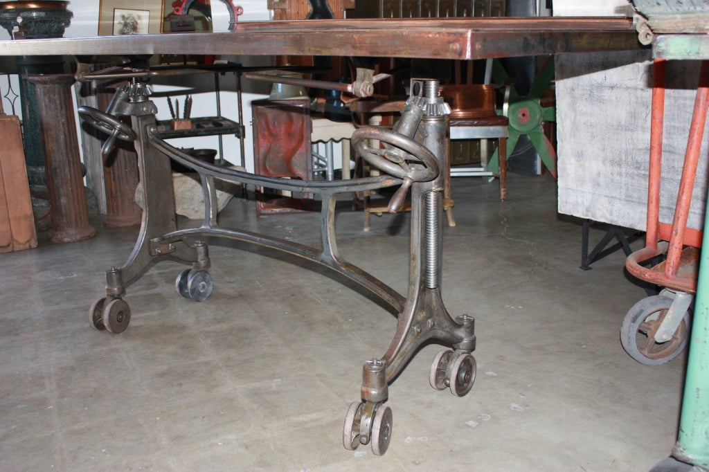 Heavy very sexy original printers table or could be used for drafting. Great casters supporting cast iron base and sheet metal top. Moves well. Can be used with top in either horizontal or vertical position. Has original clamp on top which could now