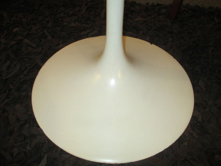 Saarinen's iconic tulip table first produced in 1956 and this one is dated 1965 when bases were still cast in iron making this table many times the weight of newer tables.  Original paint on base is in exceptional condition. top white laminate has