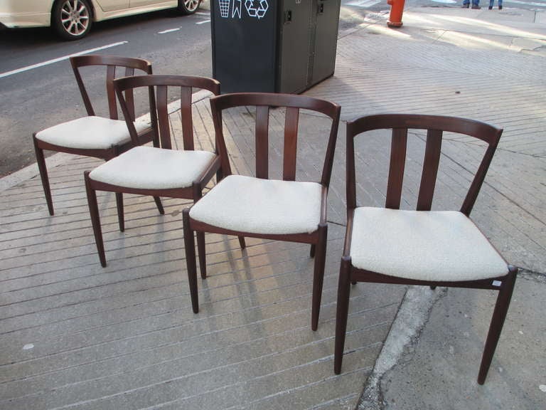 Solid teak dining chairs made in Denmark for Raymor.  Each chair retains a metal label.  Seats have been recovered in a light grey Knoll Boucle.