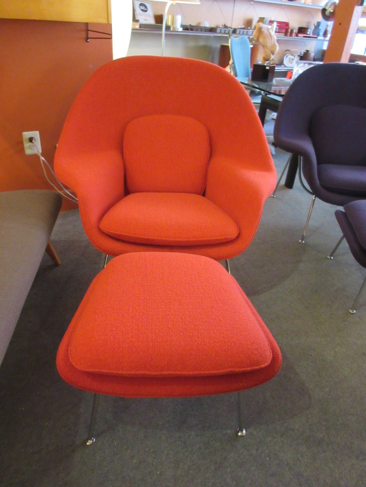 Two womb chairs with ottomans both covered in Knoll bouclé fabric, black iris and crimson. Chromes frame and legs.