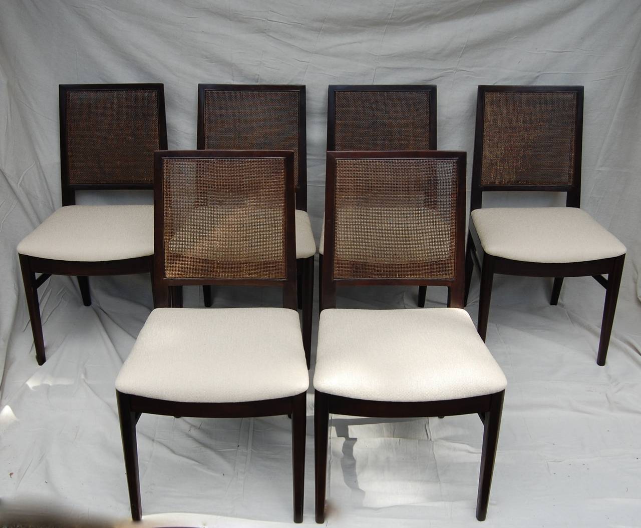 Set of 8 John Stuart Ebonized Walnut Dining Chairs.  Two Armed Chairs and 6 Armless.  Original caning in excellent vintage condition.  Newly upholstered in fine neutral cotton linen woven fabric.  Host chairs measure 21