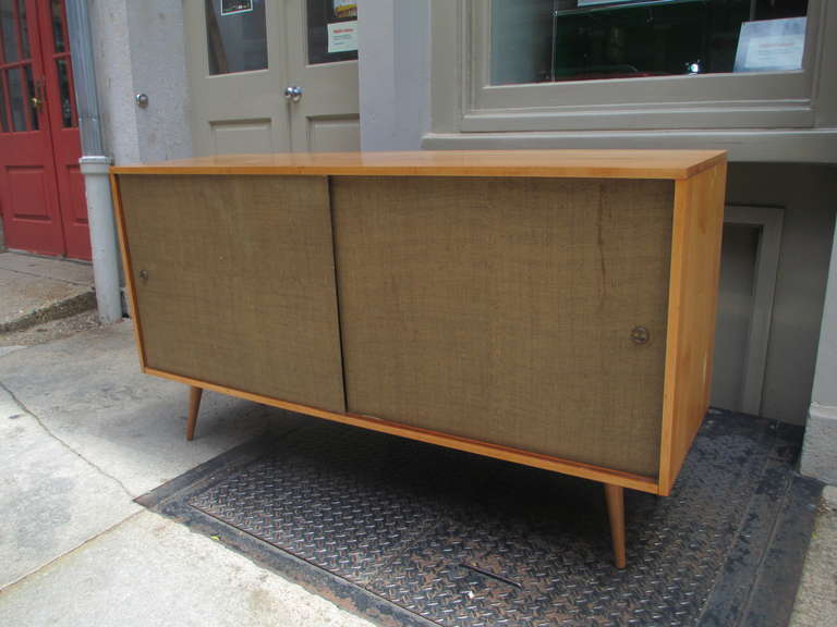 McCobb's solid birch Planner Group Credenza in all original condition including the natural grass cloth sliding doors.   Interior has four sliding drawers and room for several shelves on adjustable pegs.