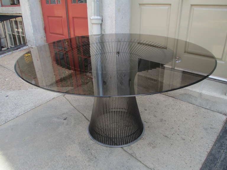 Warren Platner's iconic dining table of bent steel rods welded to three circular bands which conform to the hour glass shape of the table base done in the bronze finish. The large highly beveled top is of a bronze hue to a compliment the bronze
