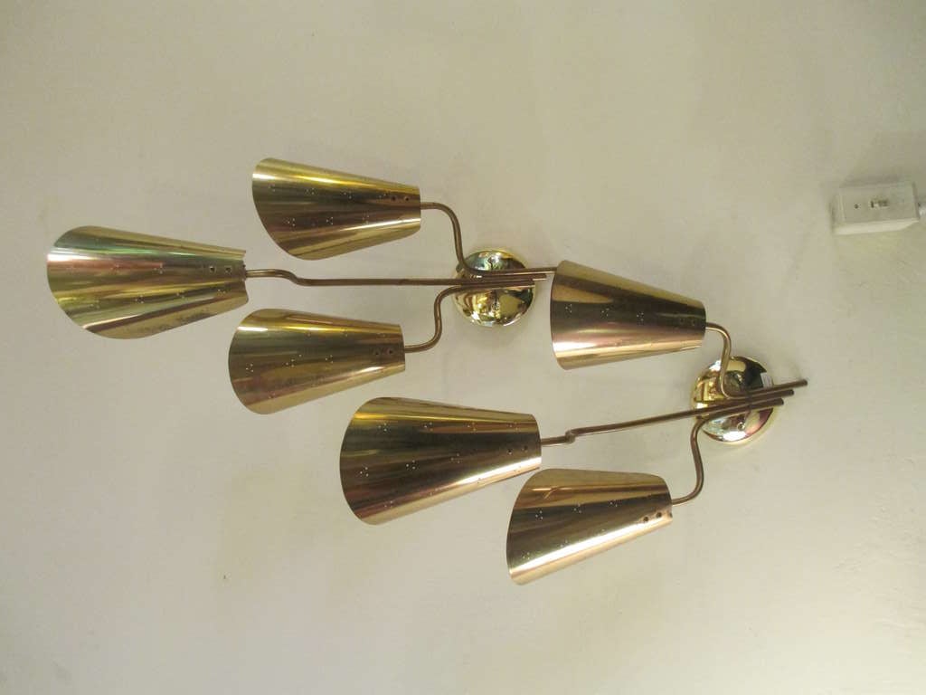  A pair of three coned perforated brass scones supported by a brass stem emanating from a single round center plate.  Each cone hides a full sized light bulb socket. 