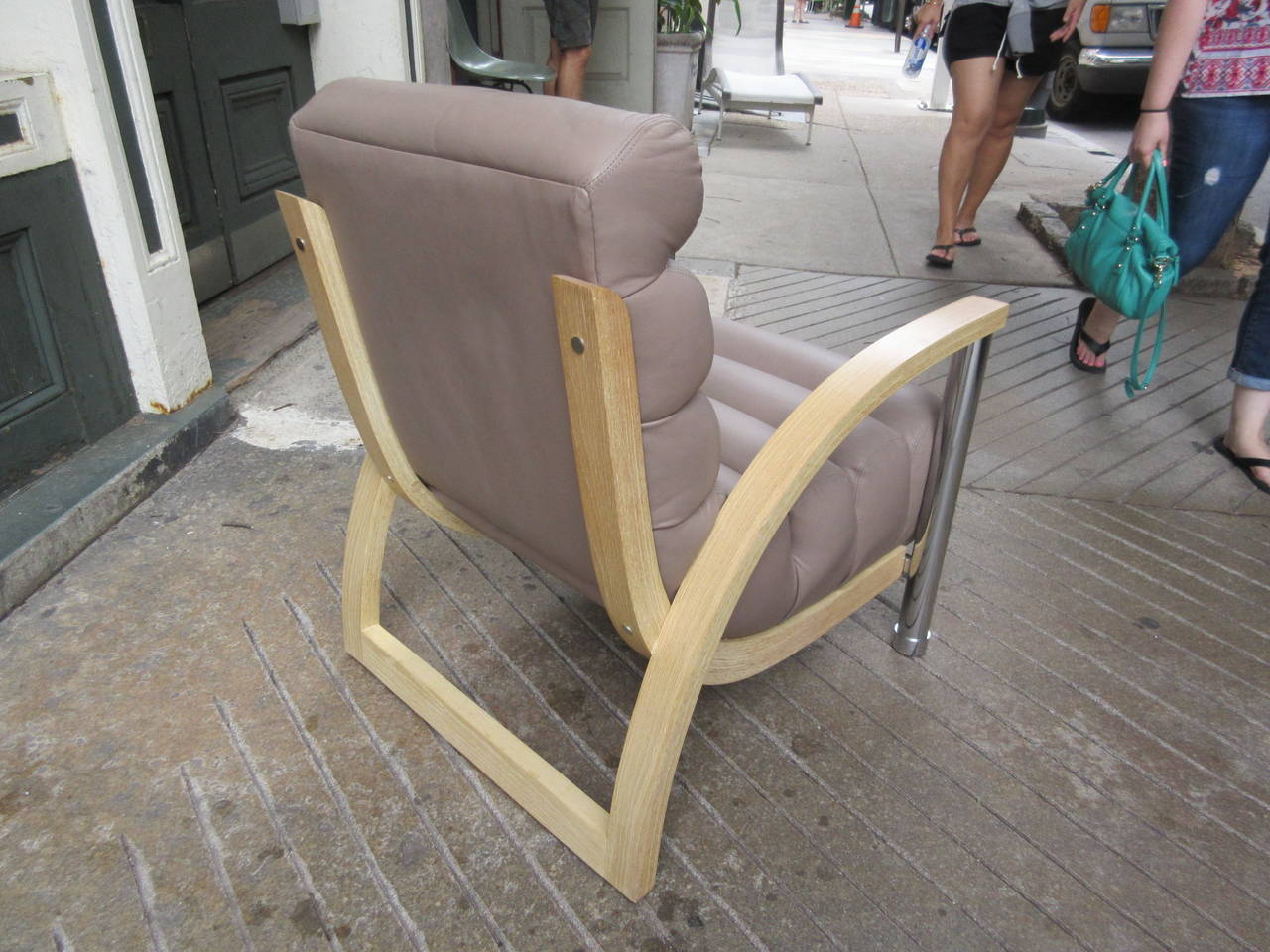 Designed in 1986 and inspired by American Art Deco this lounge chair is in taupe leather with bent bleached oak arms and chrome plated legs