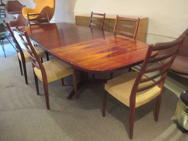 Gorgeous oval rosewood table from Gudme in Denmark on trestle base with two large leaves which are stored in the structure of the table.   Swedish chairs are of solid rosewood.  Fabric appears to have been replaced.   All wood is in excellent