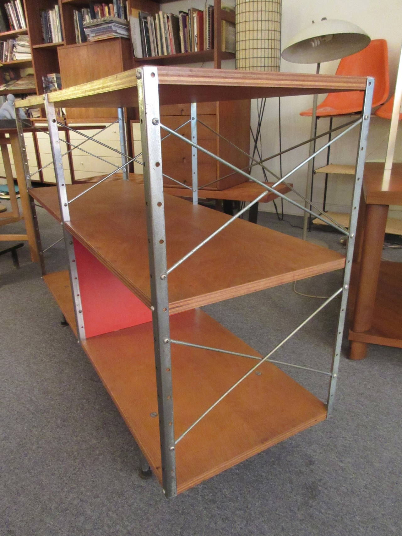 Eames 1950 design for the storage units was revised in 1952 with this more durable leg configuration. This unit retains all four original cupped feet, original wood finish, one red panel and eight X-supports.