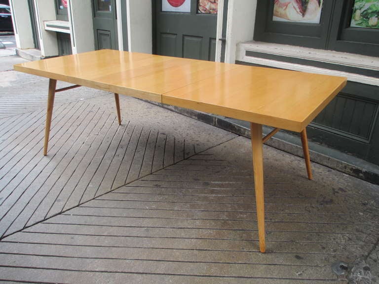 Solid maple dining table with two leaves by Paul McCobb.  Simple and elegant early 1950's design.  Burned in mark on one leaf.  Table was refinished several years ago and is still quite nice.  Without leaves it is 54 inches long and 84 with both 15