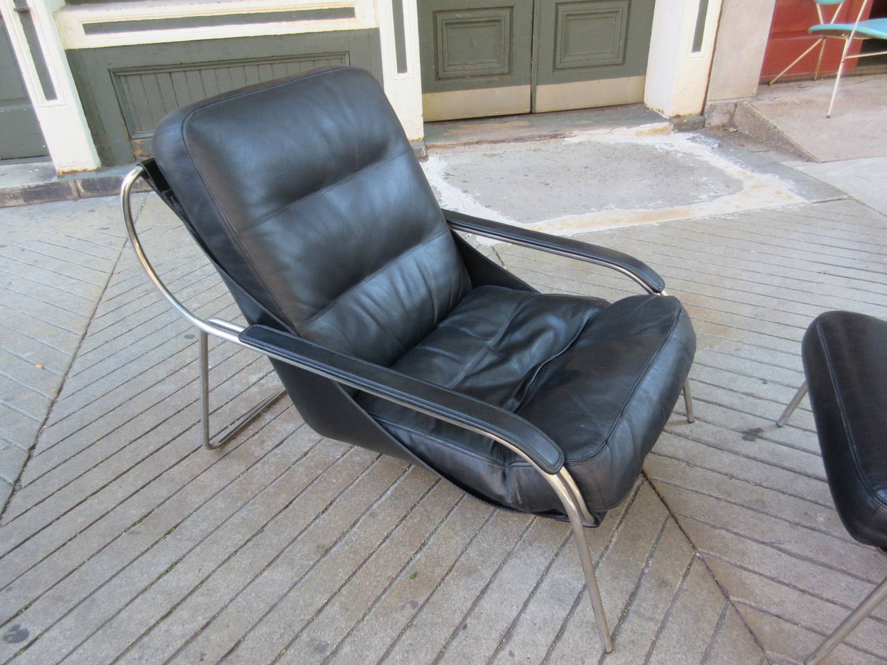 Maggiolina chair and ottoman by Zanotta designed by Marco Zanuso, 1947. Cowhide sling supports leather cushions. Stainless steel frame supports this very comfortable and sleek lounger! Ottoman measures roughly 26