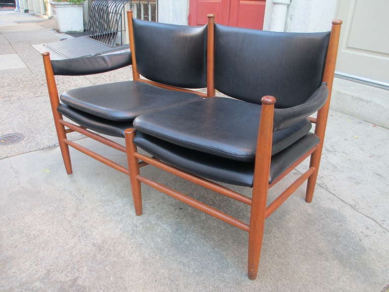 Petite settee of solid teak frame and vinyl upholstery in the manner of Kristian Vedel.  This piece was marketed through the Bon Marche store in New York City in the 1960's.  It retains its original label and is totally original and lovely.