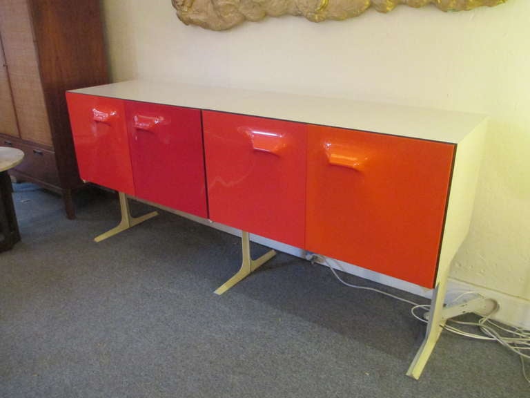 Raymond Loewy 4-door credenza in shades of orange.  Faux wood grained interior with pops of yellow pull out interior drawers.  Cabinet stands on 3 splayed legs.
