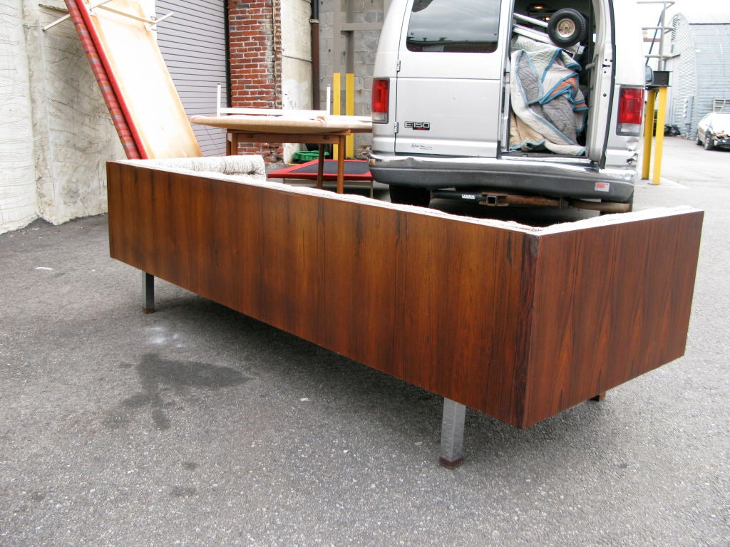 Tufted sofa with back and arms of equal height in Rosewood with chrome legs finished with rosewood feet. Upholstery is new and of multi-colored earth-tones with black leather ties instead of buttons.