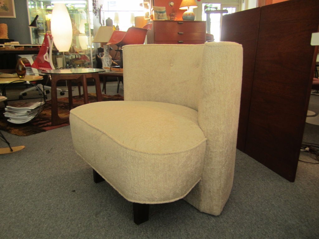 Voluptious sculptural overstuffed  1940's club chair with back that continues to the floor to form the single rear leg with two short wooden legs in front reupholstered in an off white chenille fabric