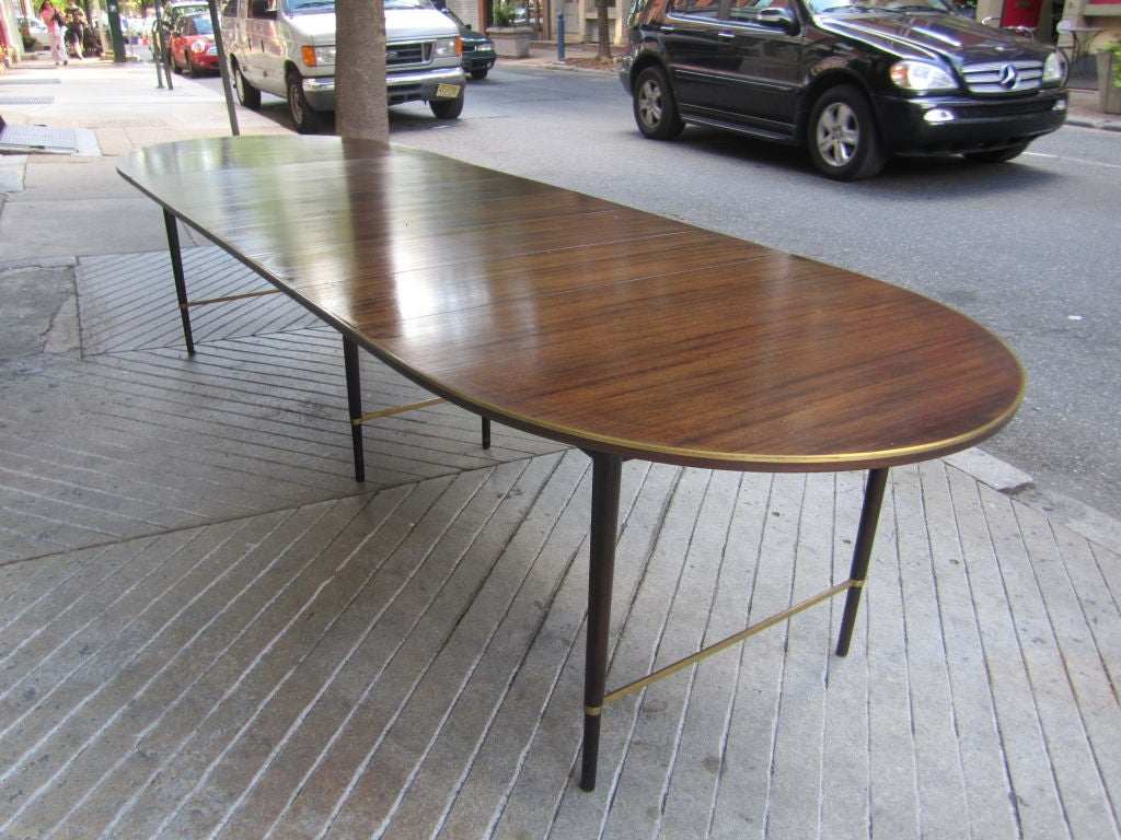 Stripped Mahogony oval extention table with six leaves trimmed in solid brass with brass stretchers between four outerlegs and inner support legs all in good original condition.  Table stretches to 128 inches with all leaves in place.  Leaves are 11