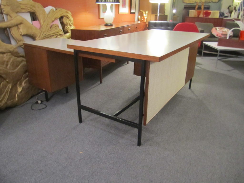 Large executive desk with return making an L shape.  Modesty panel and white formica top with three drawers on desk and file drawer on return.  Walnut with painted metal structure holding up top and drawer cabinet. Return is on a slide which allows