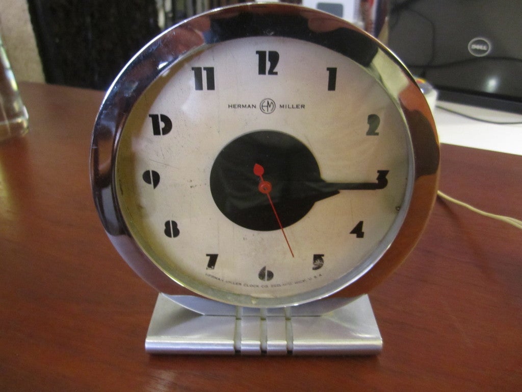 Gilbert Rohde for Herman Miller Model 4706 alarm clock designed for the Chicago Century of Progress Chicago Worlds Fair in 1933.  Frame is polished chrome with brushed chrome base.  Hands and hour numbers in black paint with red sweep hand.  Clock