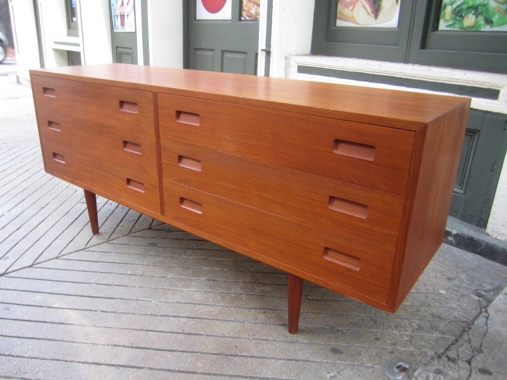 Nice 6-drawer Teak Dresser with recessed drawer pulls raised on 4 coned shaped solid Teak legs.  Retains it's original finish and burned in maker's mark on backside of cabinet.  Very Nice original Condition!  Shows a few fine scratches on top