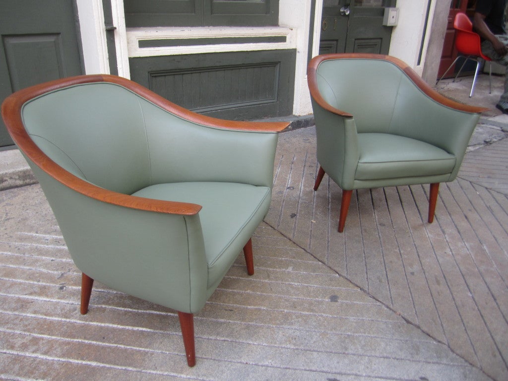 Pair of petite leather arm chairs with solid teak legs and wrap around arm trim just redone in an olive leather.