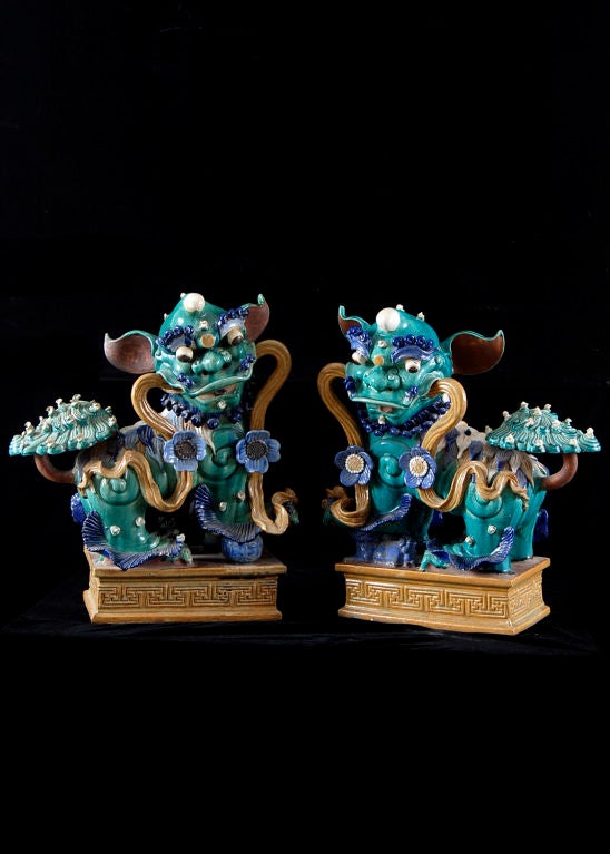 Fine Pair of Chinese Polychromed Ceramic Buddhist Lion Dogs from the Qing Dynasty Period. Traditional Chinese guardian lion dogs, with male resting his paw upon the world and the female restraining a playful cub that is on its back.
