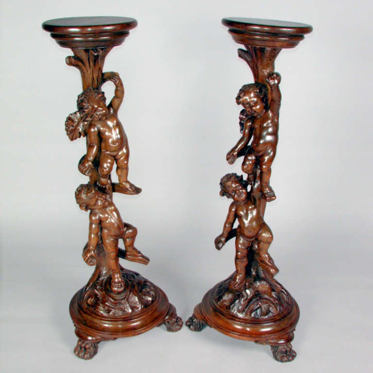 Pair of highly detailed carved wooden stands with cherubs climbing up the sides.