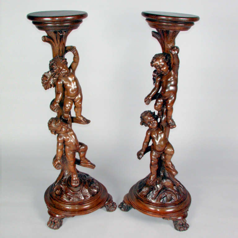 Paire de supports en bois sculpté très détaillés avec des chérubins grimpant sur les côtés.