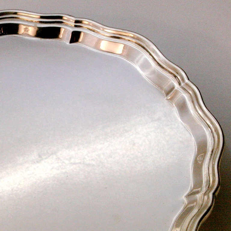 Round sterling silver tray with scalloped edges resting on scrolled feet. Hallmarked 