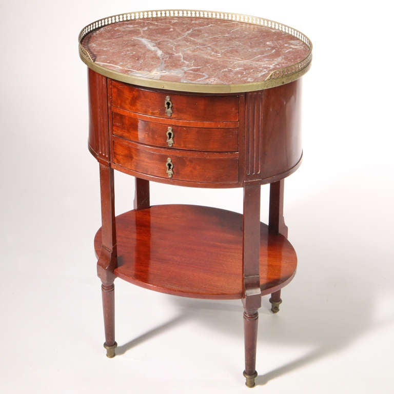 Early 19th century French oval work table with rouge marble top and brass gallery. Three drawers and oval lower shelf.