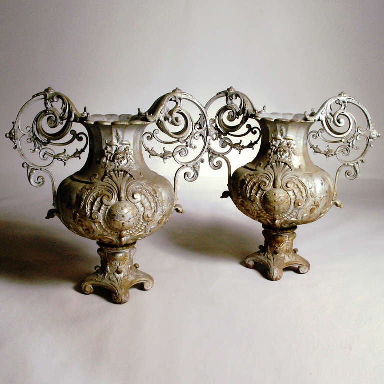 Rare pair of Victorian weathered cast iron urns with fan and flower embellishments and highly detailed large scroll handles.
