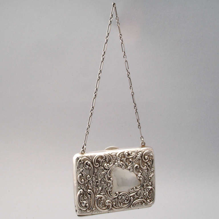 Beautiful English silver purse or chatelaine on delicate chain. Graceful design with repousse swirled scroll pattern that surrounds a heart-shaped medallion. Could be used as a card case. Hallmarked: Birmingham, 1906.