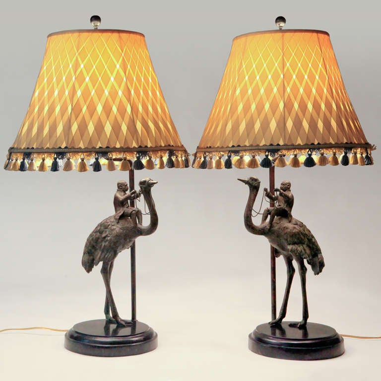 Whimsical pair of vintage metal lamps with monkeys astride ostrich figures.  Wonderfully detailed down to the monkeys' jackets and britches... and the roped halters draped from the ostriches heads to the monkeys' hands. Tasseled woven patterned