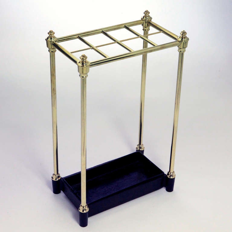 English brass umbrella stand.  Traditional design with eight umbrella sections, tall brass legs with finials and large metal drip plate.