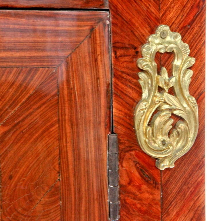 Elégant meuble d'encoignure ou d'angle en marqueterie Louis XV du XVIIIe siècle, avec portes à deux panneaux en forme de bombes et dessus en marbre rouge ajusté. Les portes de l'armoire sont dotées d'une incrustation complexe de bois brut qui forme