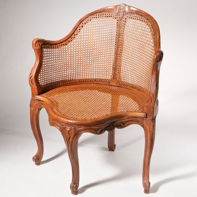 chaise d'angle française du XVIIIe siècle en noyer sculpté à la main, avec d'excellents détails. Forme lyrique avec des bras gracieux - le dossier et l'assise façonnés avec un cannage ancien. Equipé d'un coussin en cuir vert vintage.