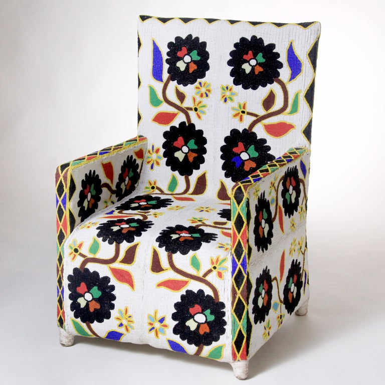 Exquisitely crafted Nigerian chair in vivid primary colors on white background.  Canvas covered wood frame chair with extensive hand beading.  African artists used native flowers bordered with geometric designs to create a vibrant pattern.  Each