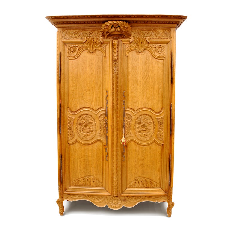 Carved oak wedding armoire with two doves under leaves and grapes on crown piece and two-panelled doors carved with grapes and birds on oval medallion. Each door is topped by large leaf.