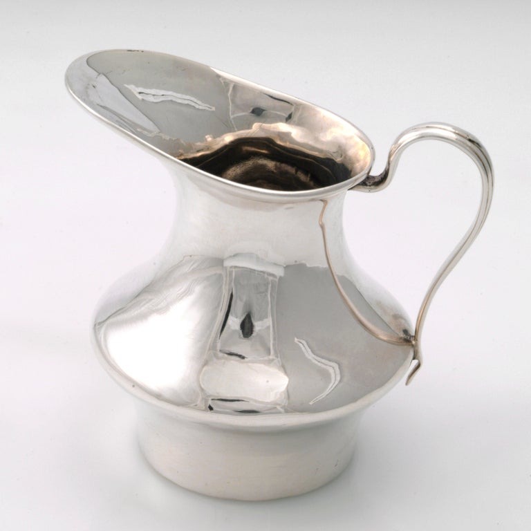 Small English silver creamer with thin handle and tapered middle. Hallmarked: London 1909.