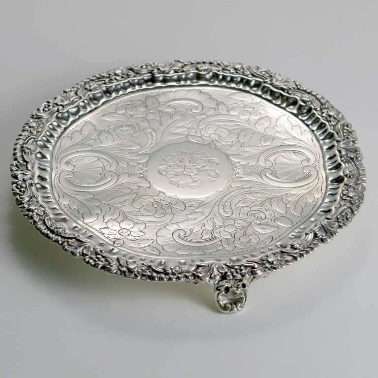 Small round engraved old Sheffield serving tray with embossed leaf and flower border and decorative raised feet. The centre medallion with coat of arms inscribed: 