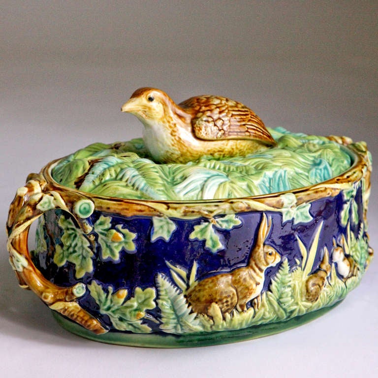 GEORGE JONES majolica game dish with twig handles, acorns and leaves.  The sides with rabbits and bunnies playing in the ferns on a cobalt background.  A nesting quail bird finial on the lid.  Marked: George Jones.  Date Code: 1875   Pattern No: 