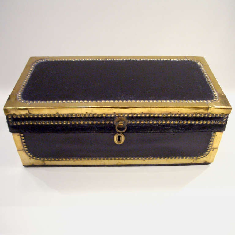 Handmade 19th century English black leather trunk. Small rectangular shape, the top and bottom edges all capped in brass and outlined with brass tacks.