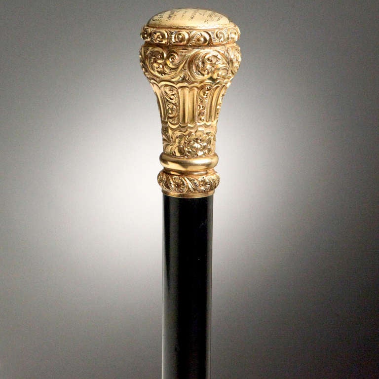 From a private old New York collection, a fine Victorian presentation cane with rolled gold knob and ebonized hardwood shaft.  Scroll and floral pattern in relief.  Top of knob engraved:  