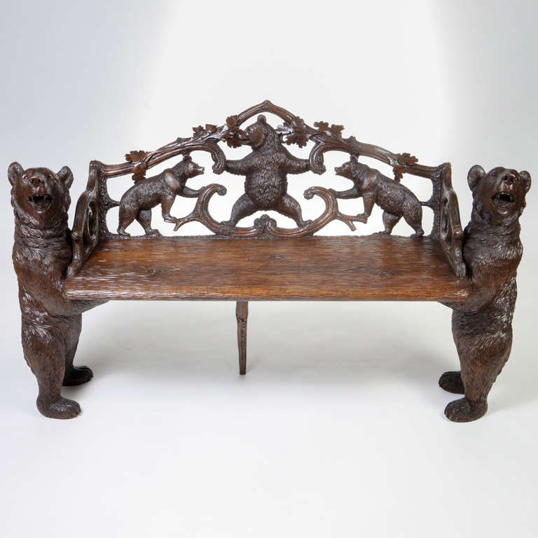 A rare European Black Forest carved linden wood bear bench. The back carved in relief with branches, leaves and three smaller bears. The seat a carved wood plank that is supported on each side by realistically carved standing bears. The small side