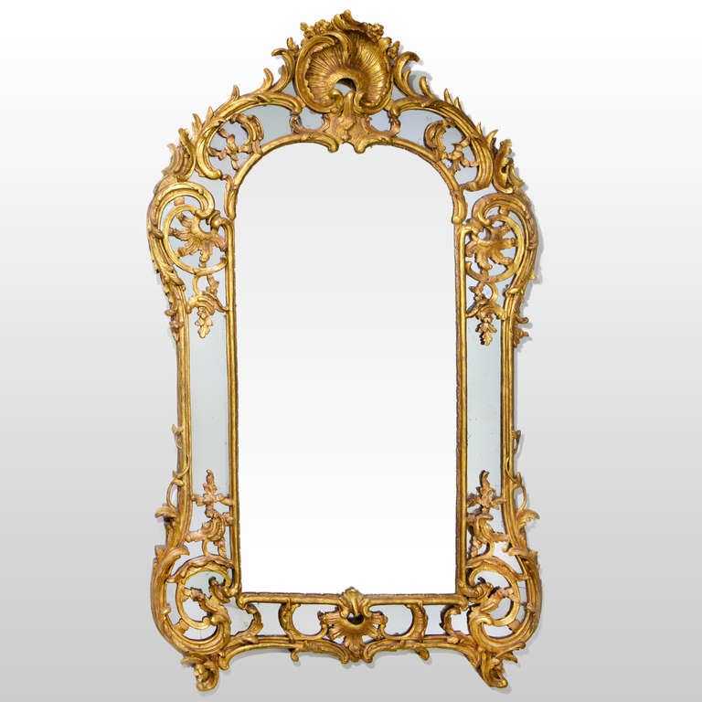 Exceptional 18th century Louis XV giltwood mirror. Large 6 foot hall mirror with carved giltwood overlay. Tall dome shaped mirror designed with large centre shell medallion, ornate scroll and leaf patterns and small scrolled feet.