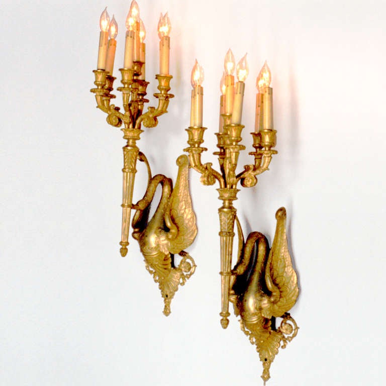 Early 19th century Austrian bronze candelabra sconces. A classic pair of swan figures in flight holding torches that are crowned with seven candle lights. Electrified.