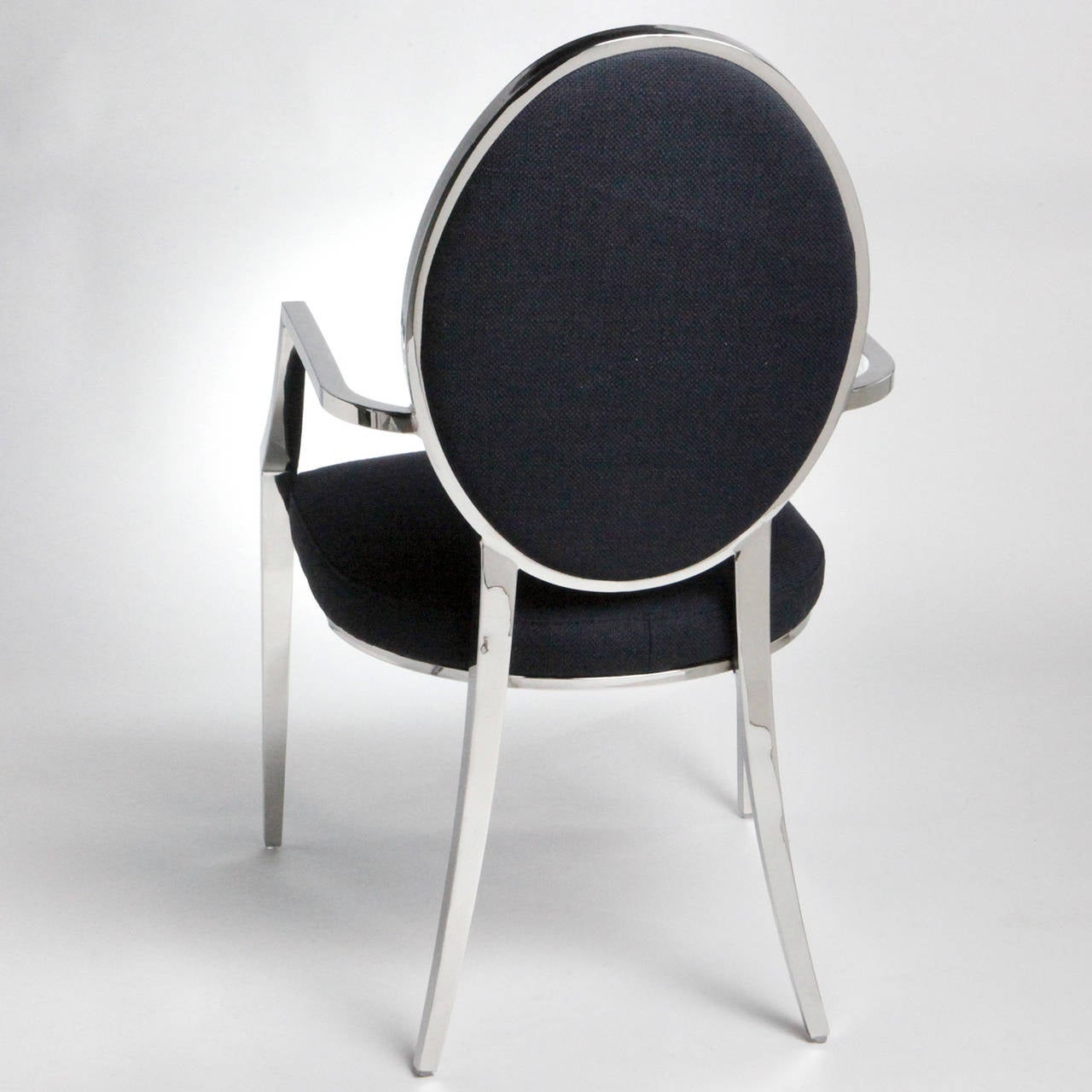 Élégante chaise classique à dossier en cuillère avec un cadre en acier inoxydable. Assise en tissu noir et dossier en tissu touffeté.