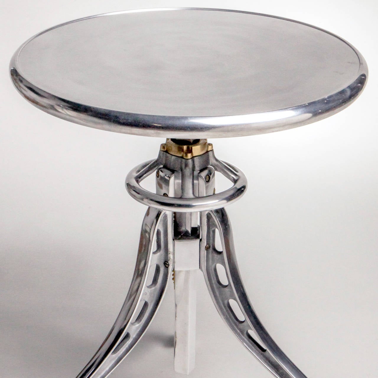 Industrial look polished aluminum table on adjustable tripod base with casters.