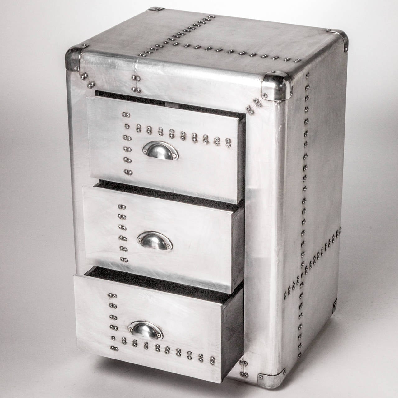 Small trunk style three-drawer polished metal chest with studs.