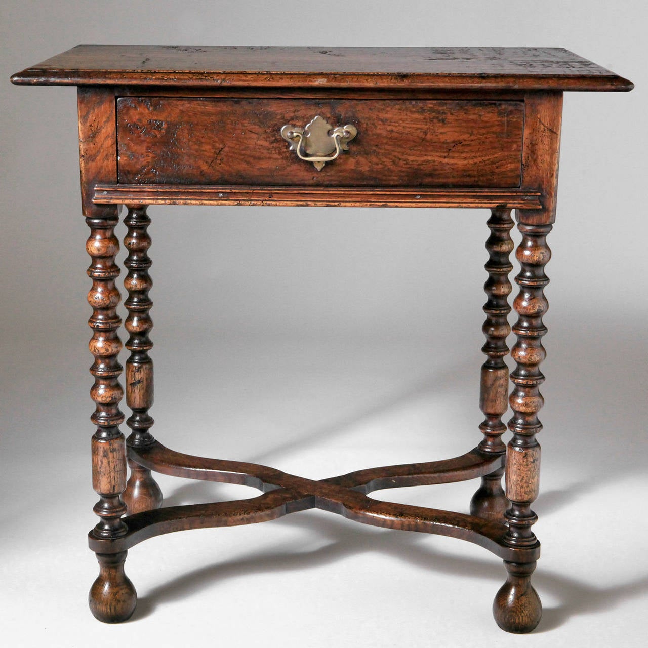 Traditional polished English oak side table with cross stretcher and barley twist legs and long front drawer. This Classic table is handcrafted in English workshops using the finest materials and antique tools to recreate a piece as Fine as the