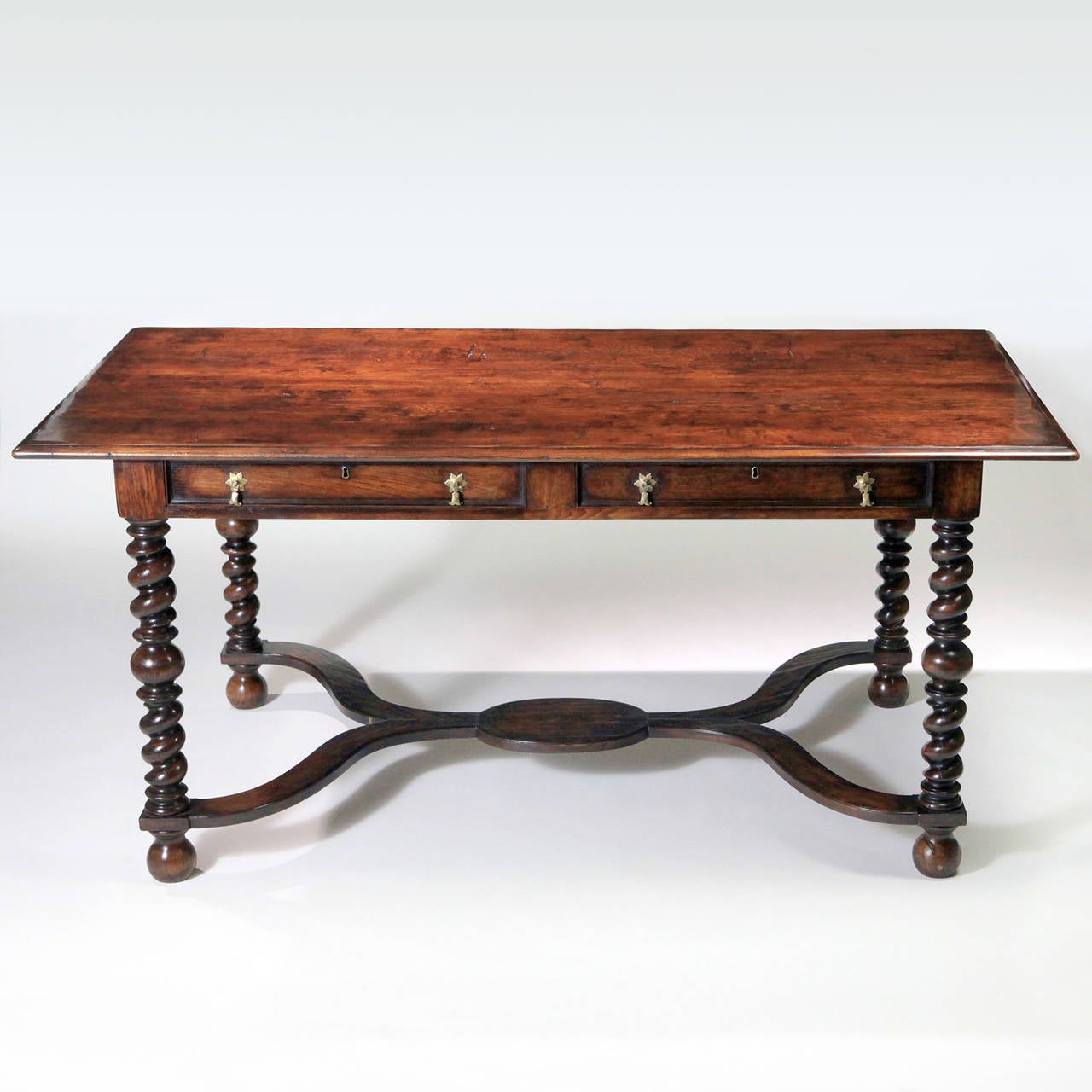 Traditional polished English oak library table with long cross stretcher and barley twist legs. The table features two long drawers with lock and key on the front side of the table and two matching faux drawers on the reverse side. This classic